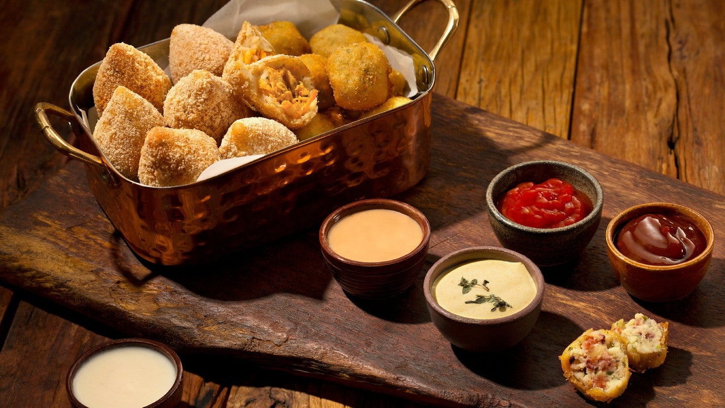 Cesta com coxinhas e outras frituras é servida com uma variedade de molhos em tábua de madeira - Quantos salgados por pessoa