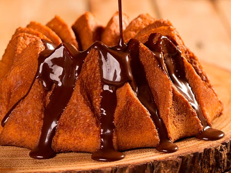 Imagem mostra cobertura de chocolate caindo e escorrendo sobre bolo – Ideias para Páscoa 2024.