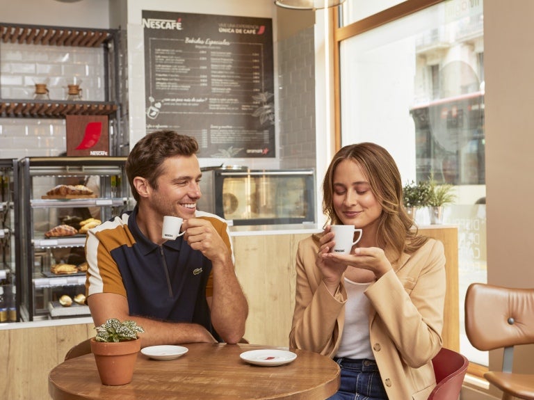 Um homem e uma mulher tomando café Nescafé em uma padaria