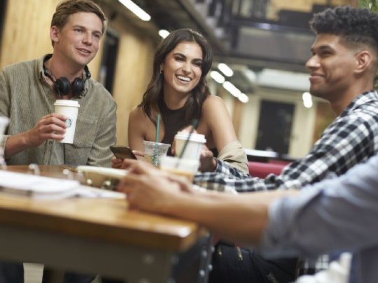 Jovens conversando e rindo e bebendo produtos starbucks