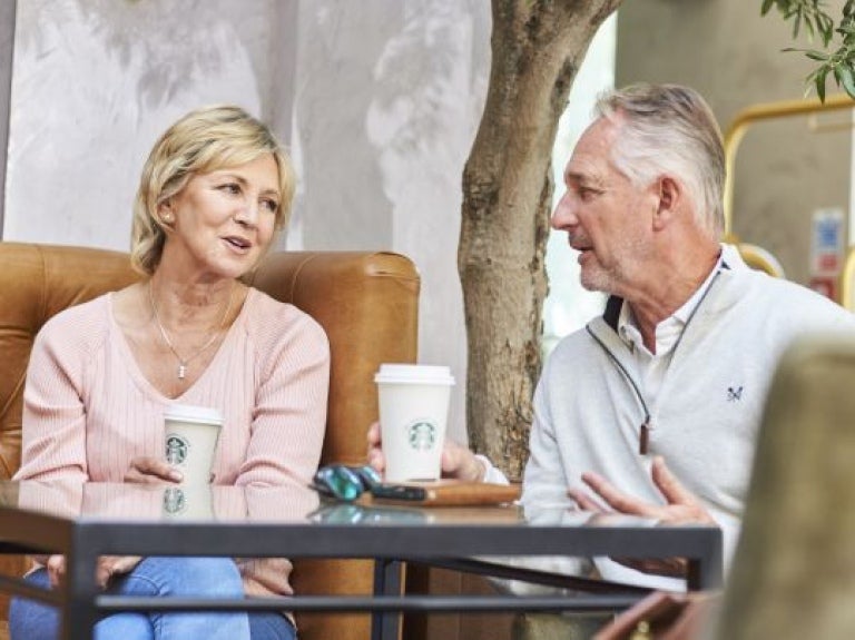 Casal feliz conversando em uma praça tomando produtos starbucks