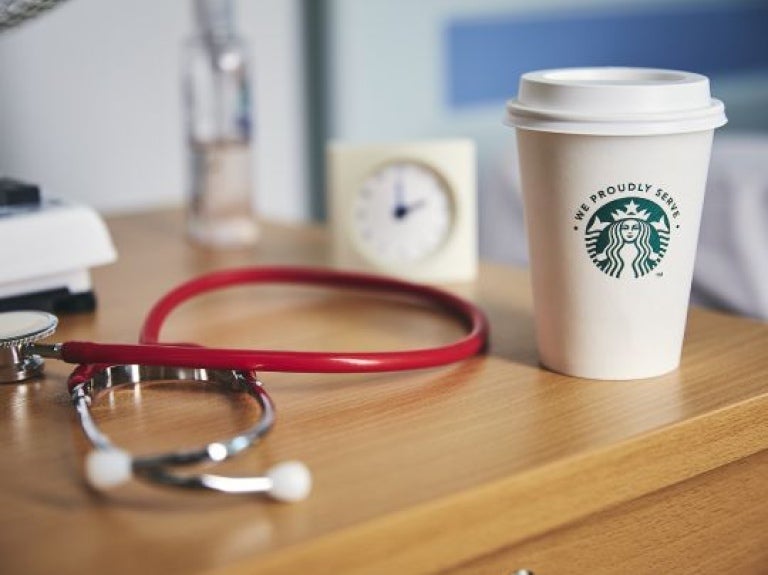 Imagem de um quarto, com uma mesa de canto contendo produtos starbucks