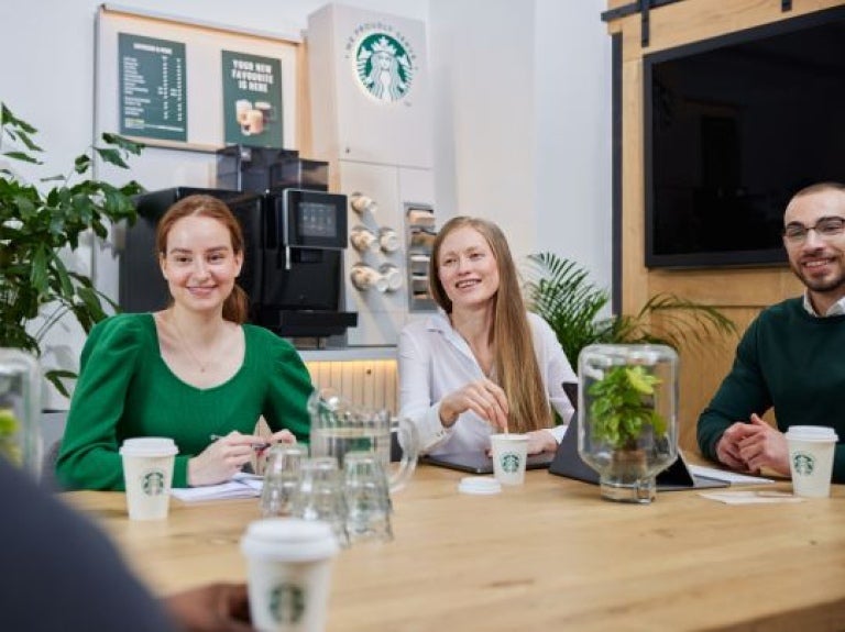 Espaço de reunião contendo profissionais que estão bebendo produtos starbucks