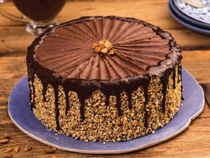 Bolo de chocolate decorado com pedaços de amendoim ao seu redor e na cobertura - Charge chocolate