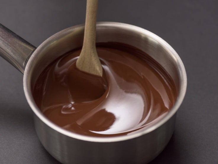 Chocolate derretido em uma panela de alumínio sendo mexido por uma colher de pau - chocolate nestlé