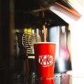 Bebida de chocolate KitKat sendo extraída da máquina de café em copo vermelho com a marca kitkat estampada