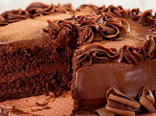 Bolo trufado feito com pão de ló redondo de chocolate, recheado com ganache e coberto com decorações feitas com ganache