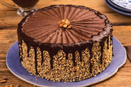 Bolo de chocolate decorado com pedaços de amendoim ao seu redor e na cobertura - Charge chocolate