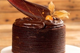 Bolo de frutas amarelas e chocolate redondo feito com massa de chocolate e recheios intercalados de chocolate meio amargo