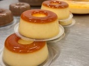 Imagem mostra mini pudins de caramelo salgado empilhados; eles tem uma aparência brilhante graças ao uso da embalagem