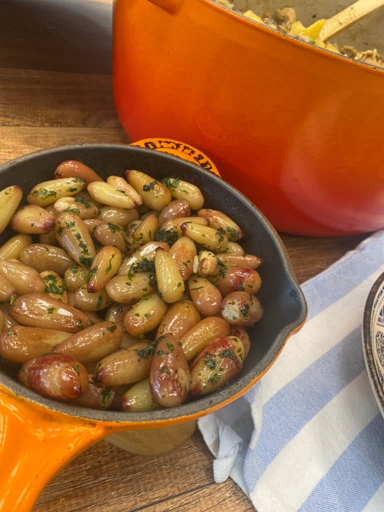 sopa de abóbora servida em uma tigela de cerâmica branca sobre uma tábua de madeira.