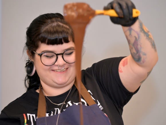 Mulher profissional gastronômica mexendo calda de chocolate